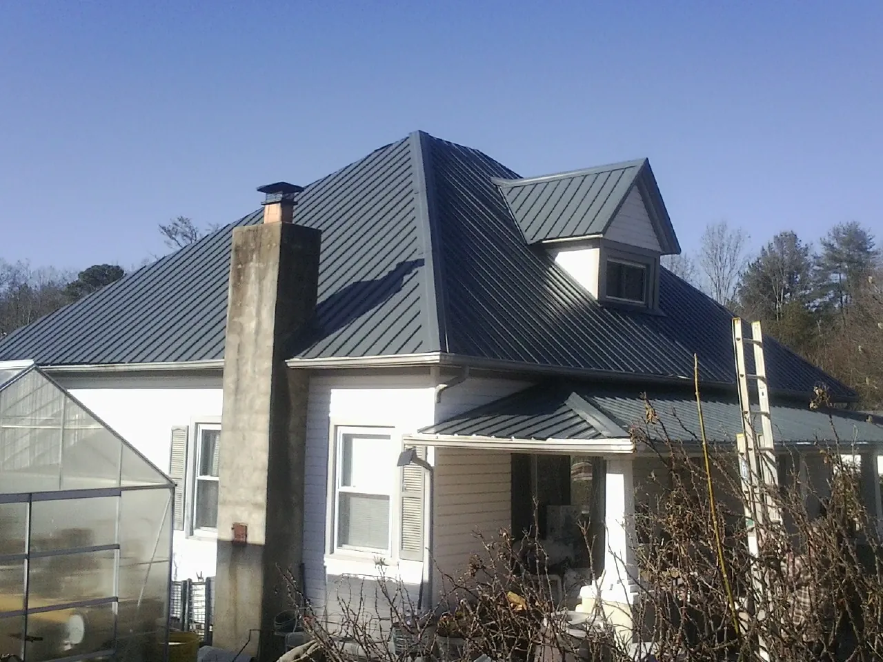 Dark blue standing seam metal roof on a white farmhouse with dormer — Slate & Tile Roof Repair by Roofing Brothers in New Church