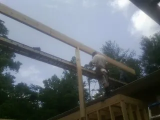 Carpenter setting a ridge beam over a new addition frame — Ice Dam Removal by Roofing Brothers in New Church