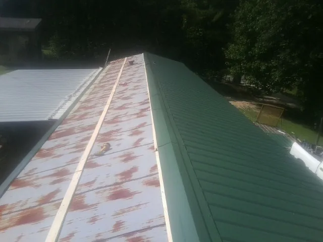 Old rusted panels beside newly installed green metal roofing — Wind Damage Roof Repair by Roofing Brothers in New Church