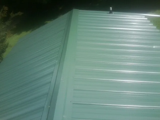 New green metal panels meeting at the ridge of a roof — Flat Roof Repair work by our crew in New Church
