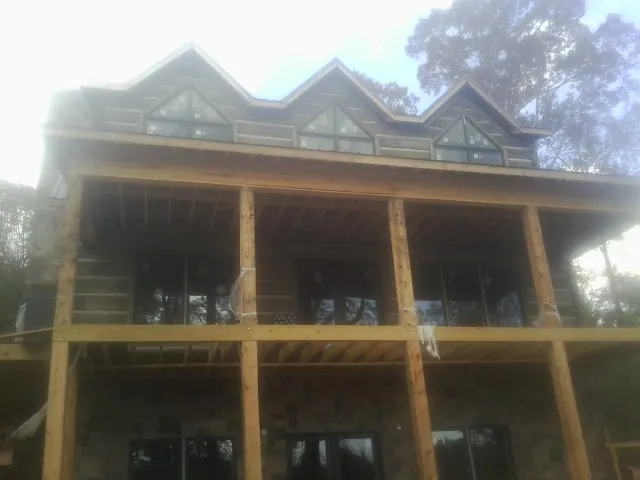 Dormers and porch framing on a large log home under construction — Roof Coating work by our crew in New Church