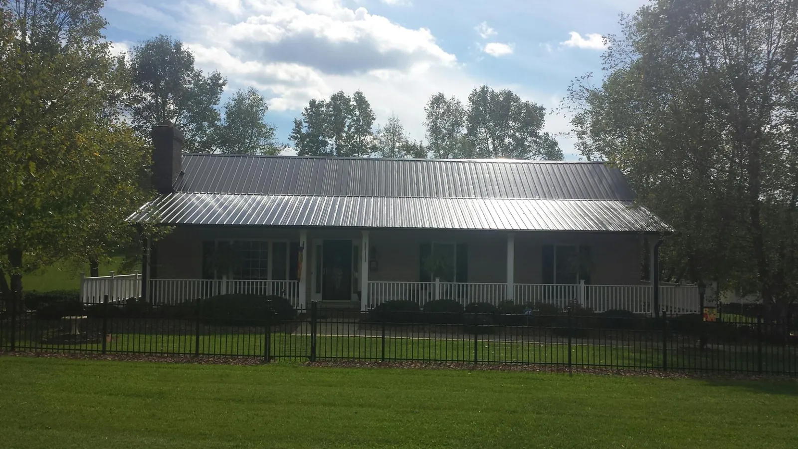 Gray metal roof on a brick ranch with a full width front porch — Gutter Guard Installation work by our crew in New Church