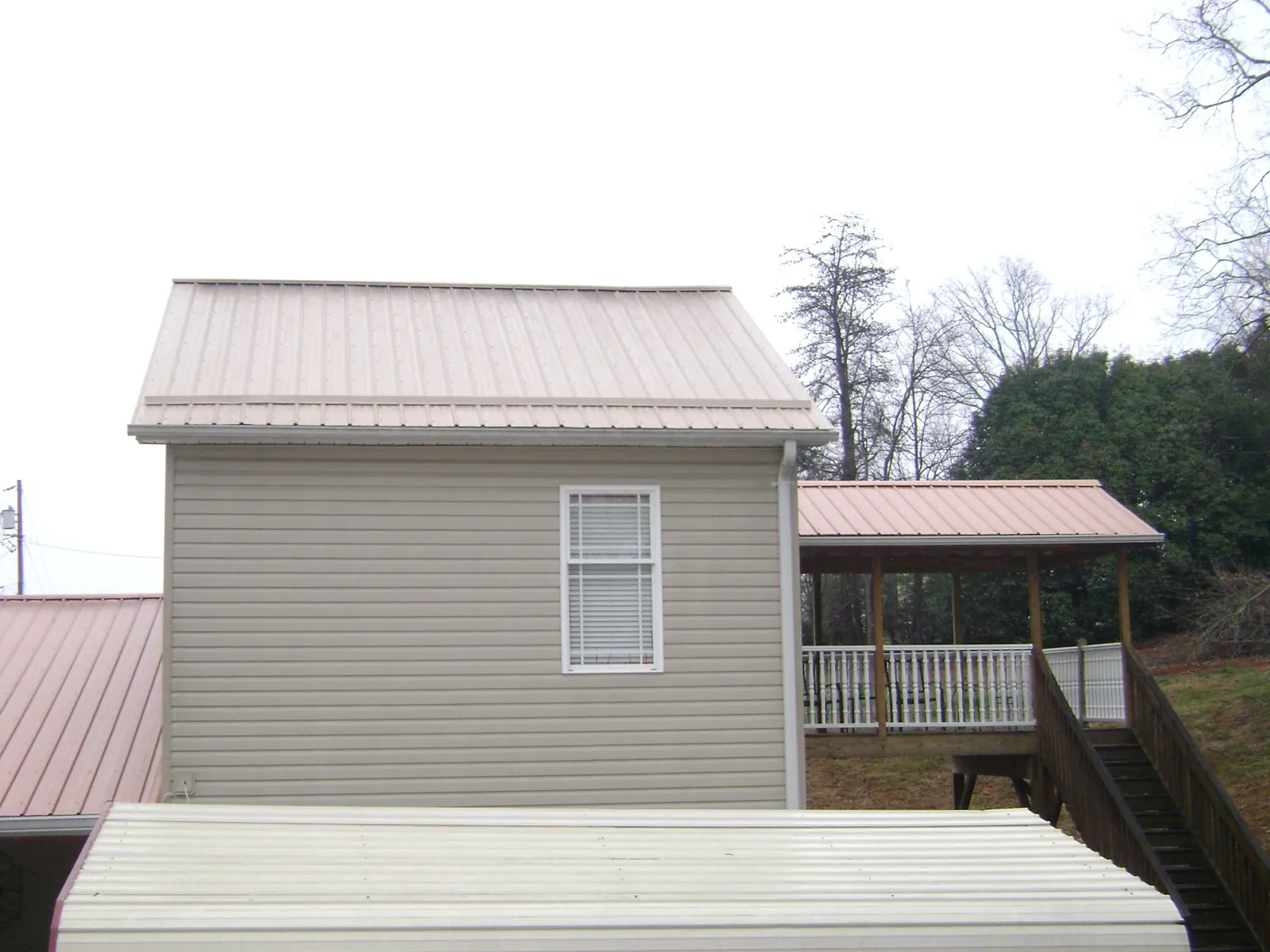 Tan metal roofs on a two story addition and attached porch, from a Roof Replacement job in New Church