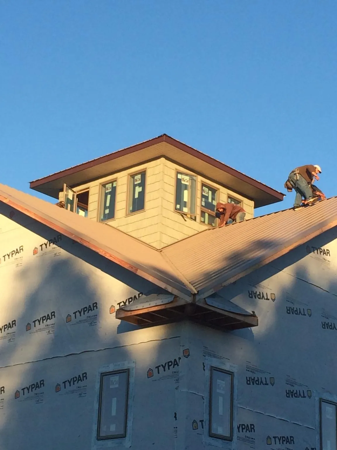 Roofers working around a rooftop cupola on a new metal roof at sunset — Roof Waterproofing in New Church by Roofing Brothers